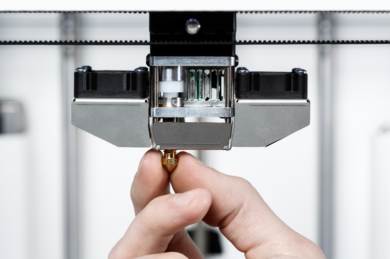 a man adjusting the nozzle of a 3d printer extruder