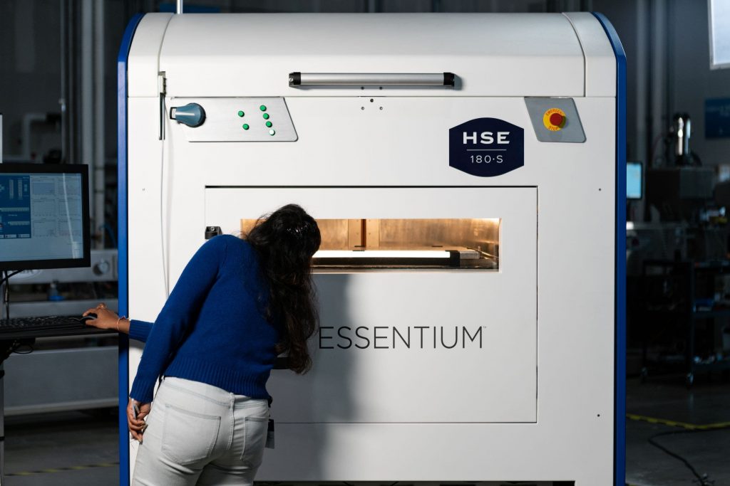a woman looks inside a large essentium hse 180s 3d printer