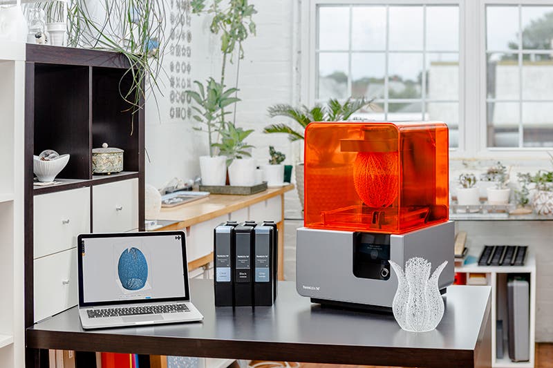 a desktop with a laptop with preform software open and a formlabs 3d printer