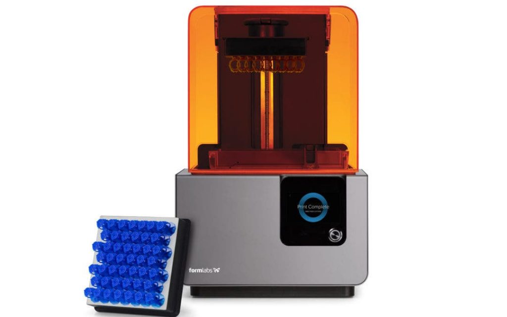 a formlabs form 1 3d printer next to a build plate full of blue objects