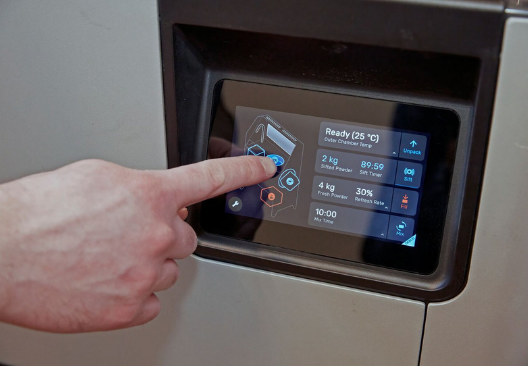 A man operating the touchscreen interface of a FUse 1 3D printer