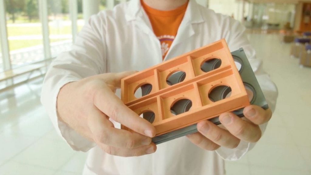 man holding two different 3d printed parts from the hp jet fusion
