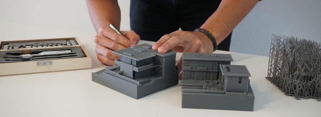 an artist drawing on a 3d printed scale model of a house