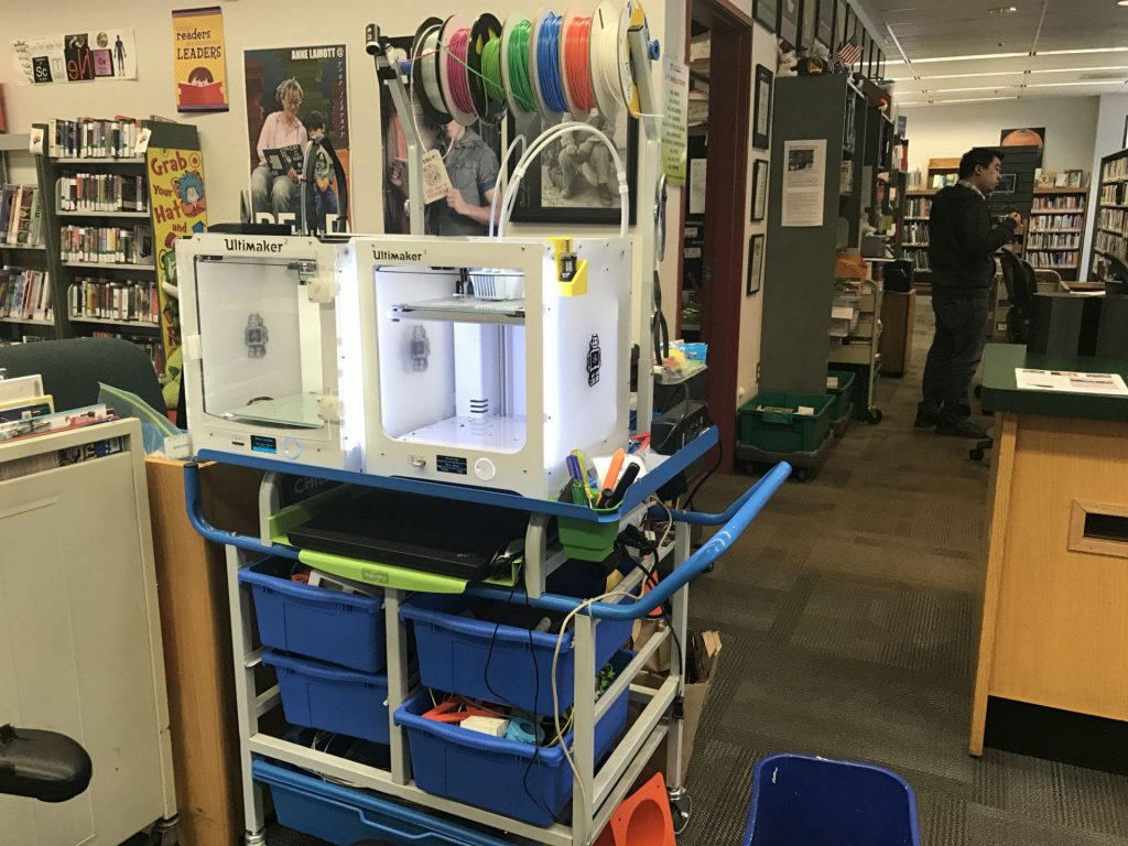 two ultimaker 3d printers in the marin city library, one of which has a material system connnected