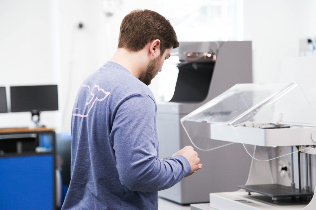 a man stood operating a 3d printer for educational purposes