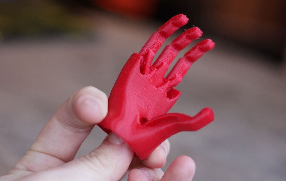 a man holding a 3d printed miniature red hand