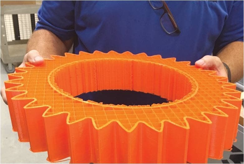 a Progress Rail employee holding a large 3d printed wheel