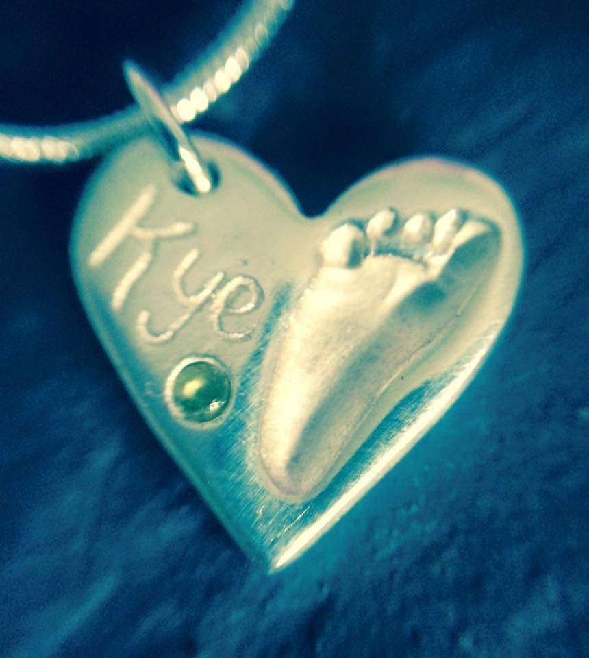 a 3d printed necklace with a baby's footprint and the name "kye"