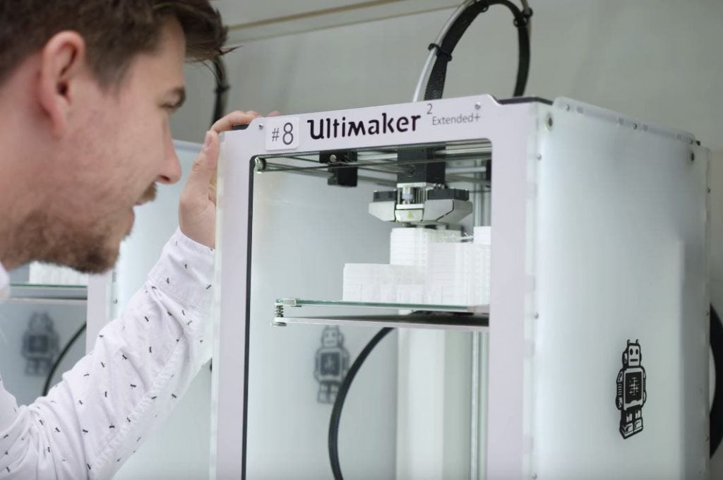a man lookos inside an ultimaker 2 3d printer