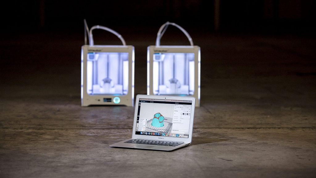 two ultimaker 3d printers along with a laptop with cura software open