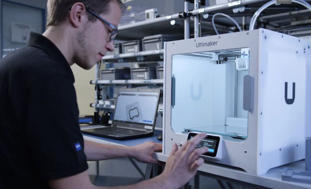 man operating an ultimaker ziess printer with software open on laptop nearby