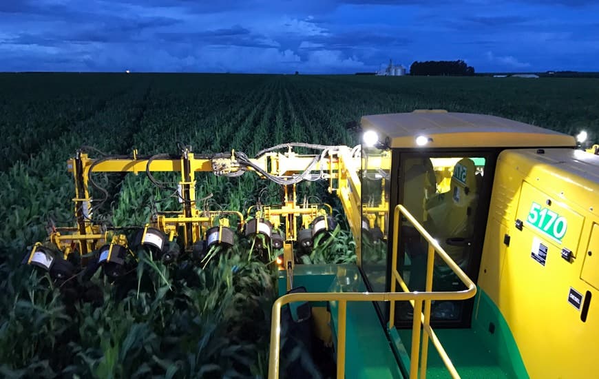 a combine harvester working in low light in a corn field