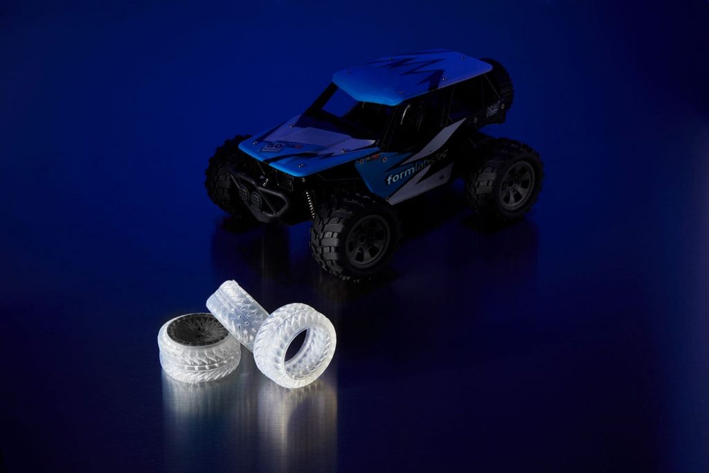 a small electric car pictured beside three 3d printed car tires