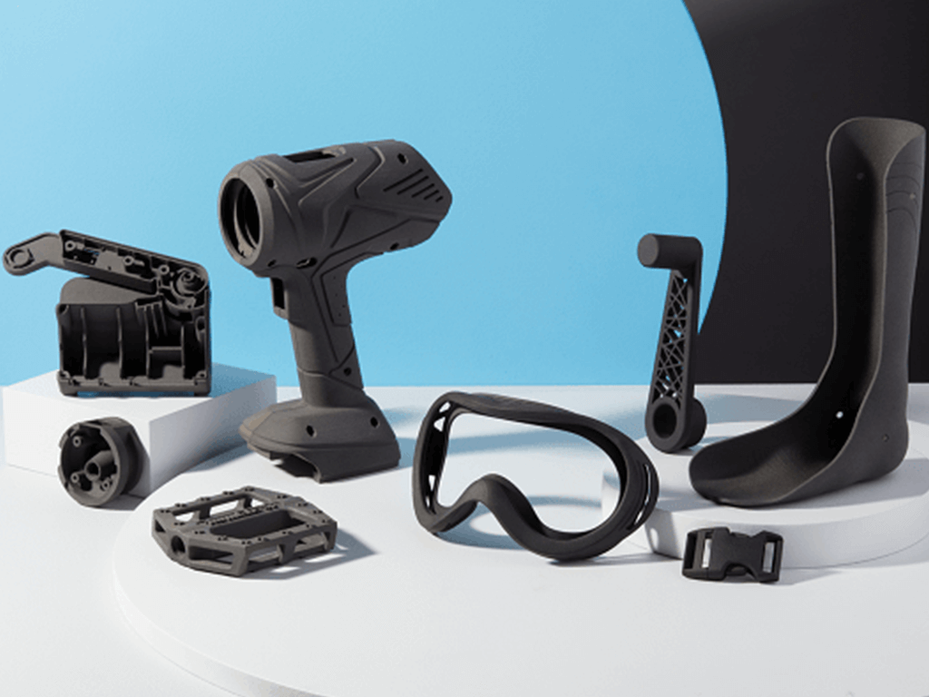 an assortment of sls 3d printer parts including a bike pedal, goggles, and belt buckle