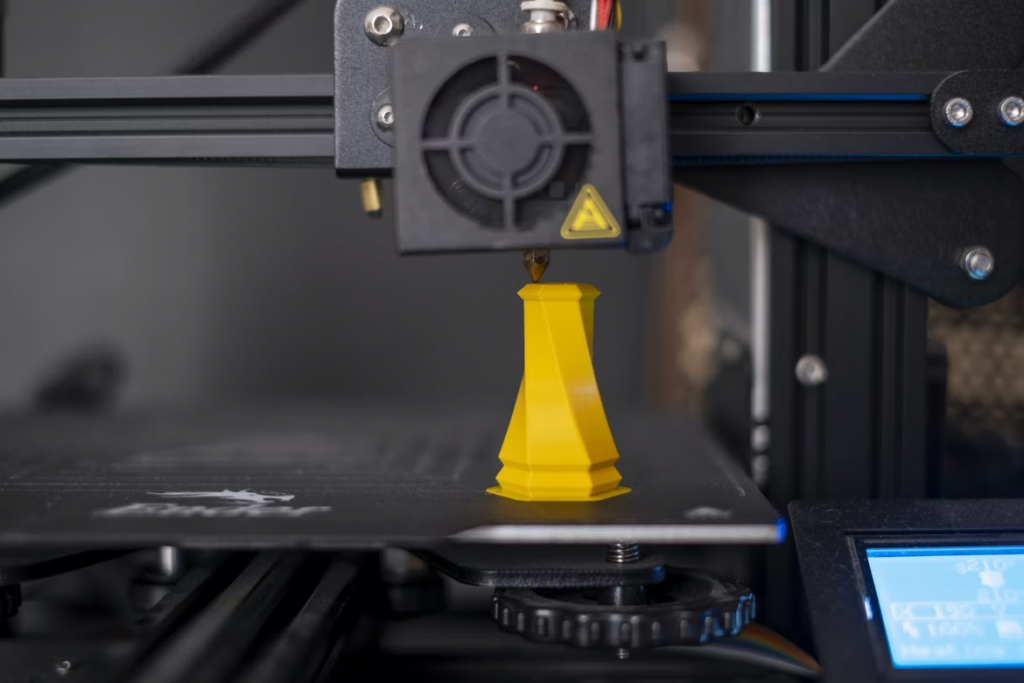 A Markforged 3D printer producing a yellow cone-like print.