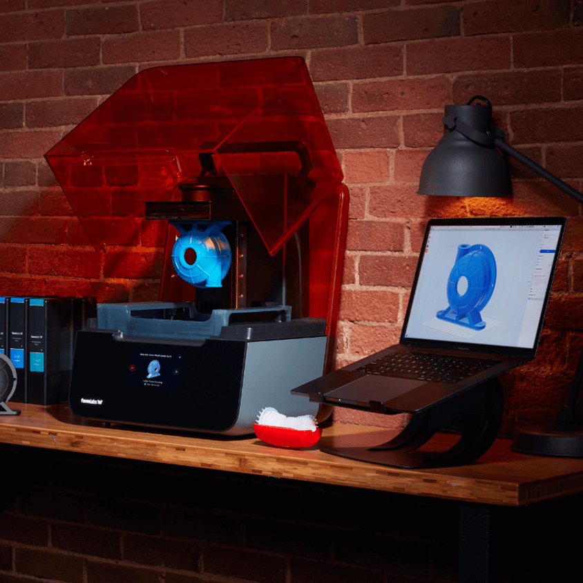 A formlabs 3D printer with a laptop showing the current print live.