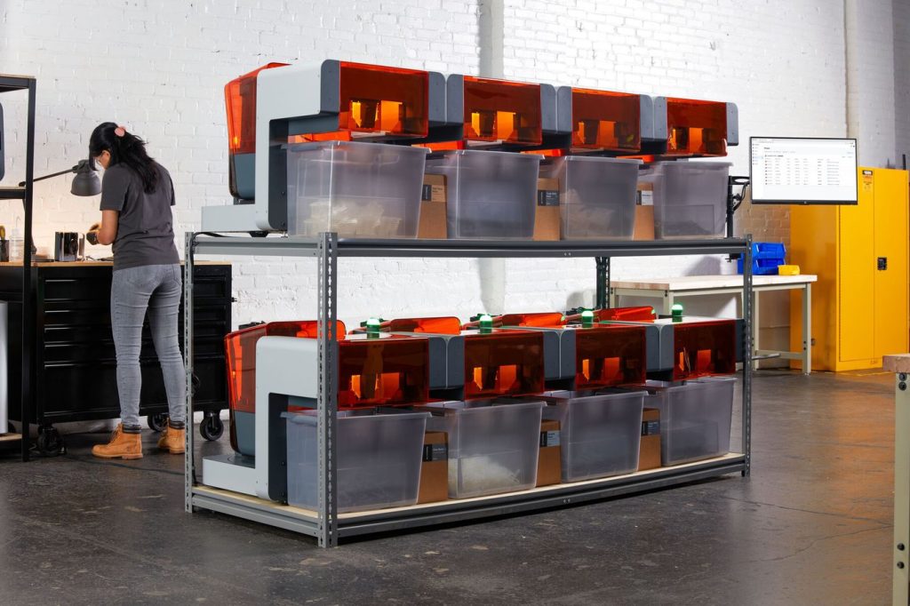 Two rows of Formlabs 3D printers with hoppers behind them, part of the automation system.