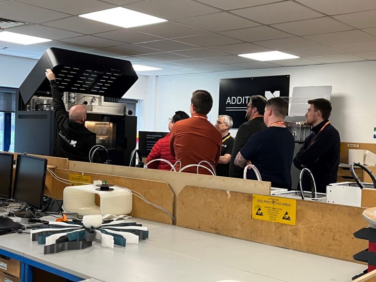 An Additive-X employee showing visitors the Markforged Metal X printer.