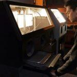 Operator using the Formlabs Fuse Sift X1 powder recovery station to depowder SLS parts