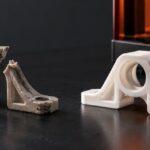 Broken plastic spare part beside a replacement 3D-printed component on a dark workbench, illustrating 3D printing spare parts for ageing equipment and repair versus replacement.
